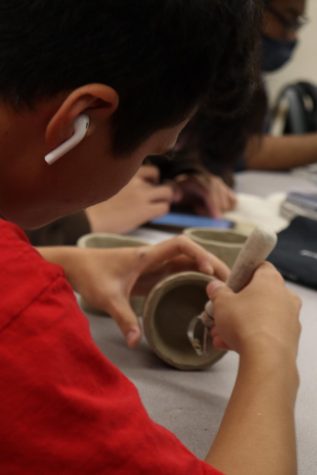 Dane Francisco carves out the inside of his mug while listening to music on his Air Pods.